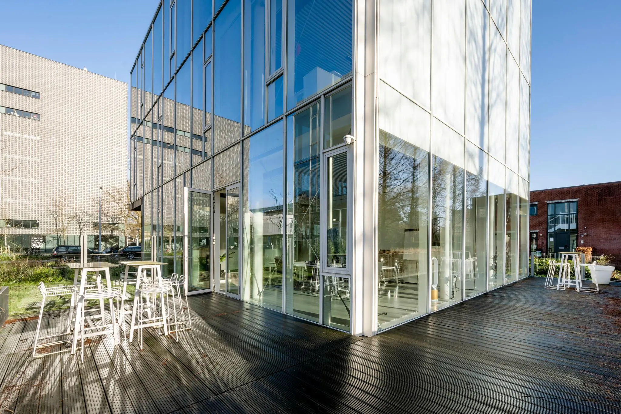 Moderne glazen gevel met terras en zitplekken aan de Fred. Roeskestraat in Amsterdam.